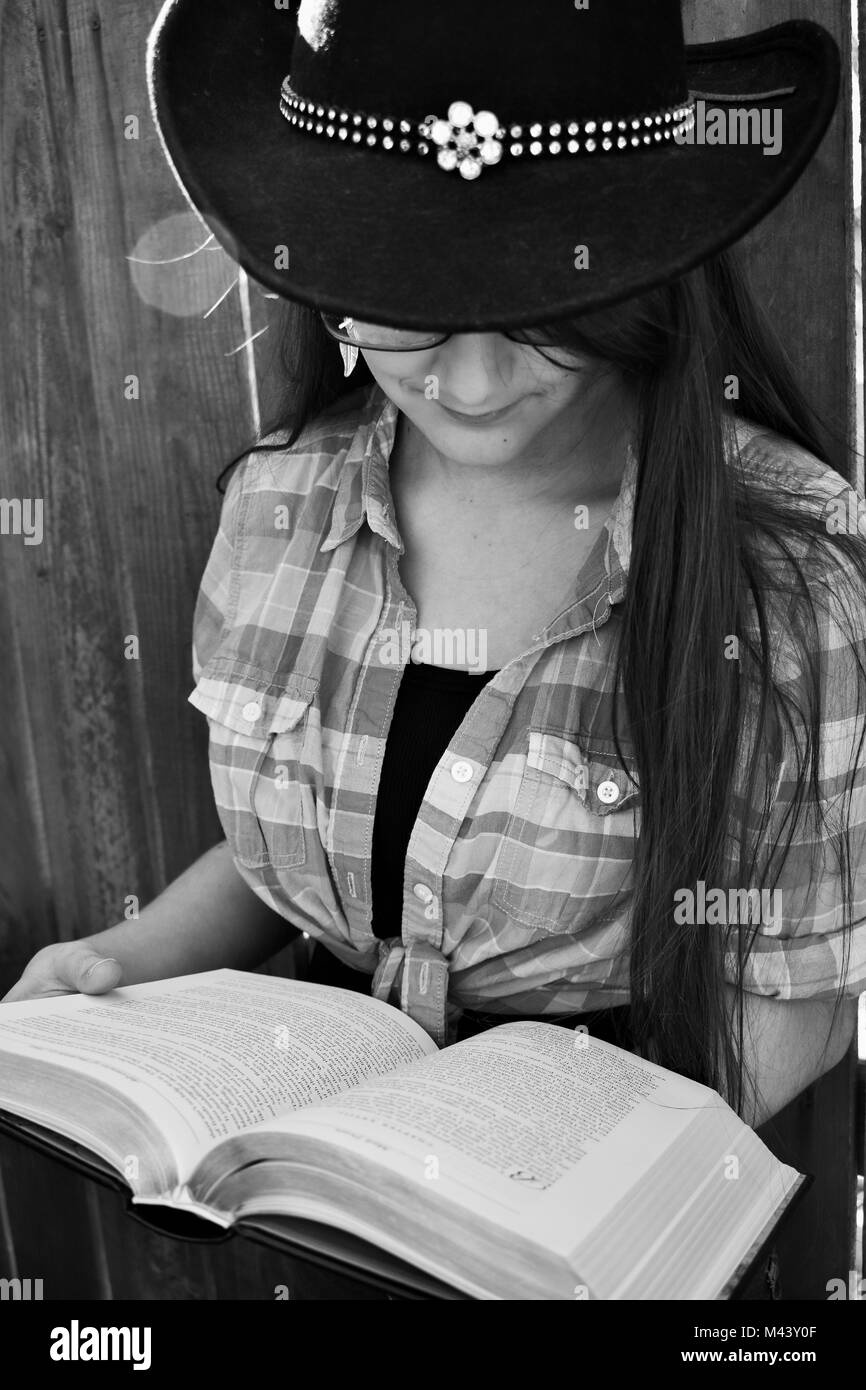 Land Mädchen lesen Ein Abenteuer Buch gegen einen Holzzaun, Schwarz und Weiß Stockfoto