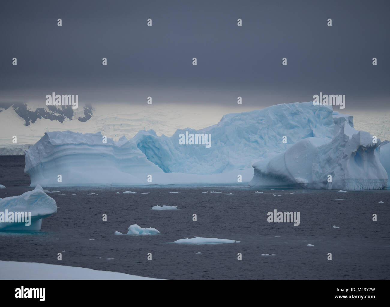 Ein großer Eisberg mit Risse und Furchen floating in Charlotte Bay in der Antarktis. Dichte Wolken sind Gemeinkosten und abgehackt Stahl grau Wasser in der Front. Stockfoto