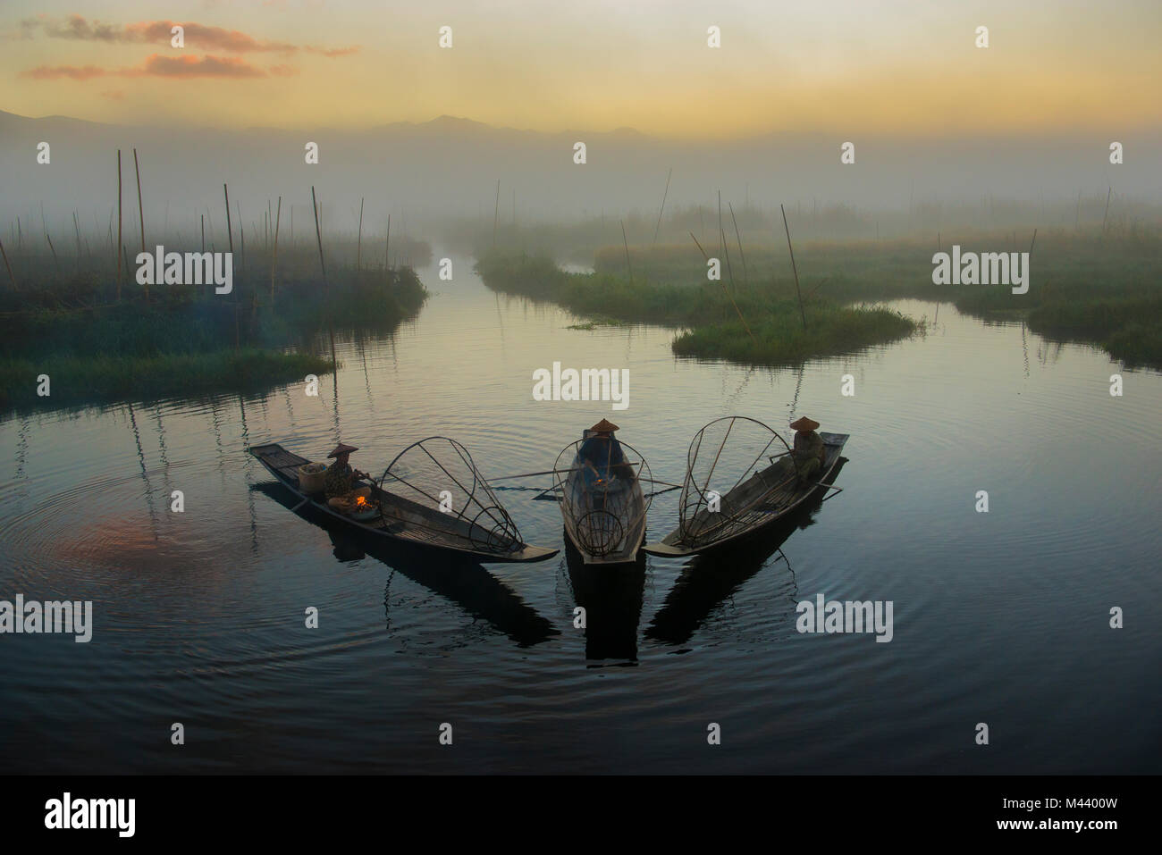 Myanmars balancing Fischer sind geschickt auf einem Bein zu stehen ausgebildete und Paddeln mit den anderen während der Jagd karpfen fisch. Stockfoto