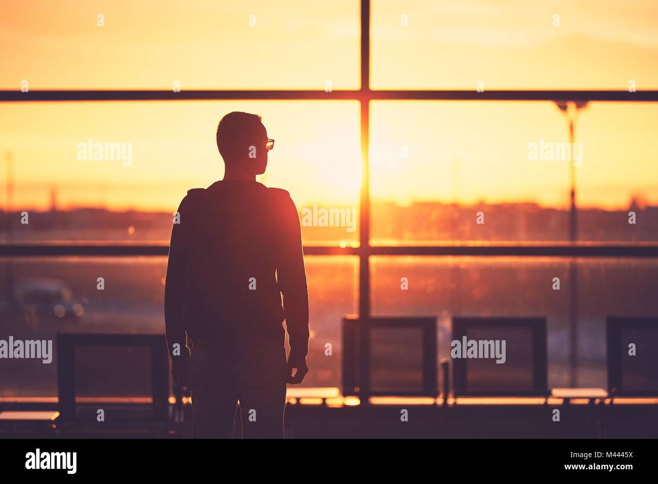 Silhouette der junge Mann am Flughafen. Traveler Blätter zum Tor während der goldenen Sonnenuntergang. Stockfoto