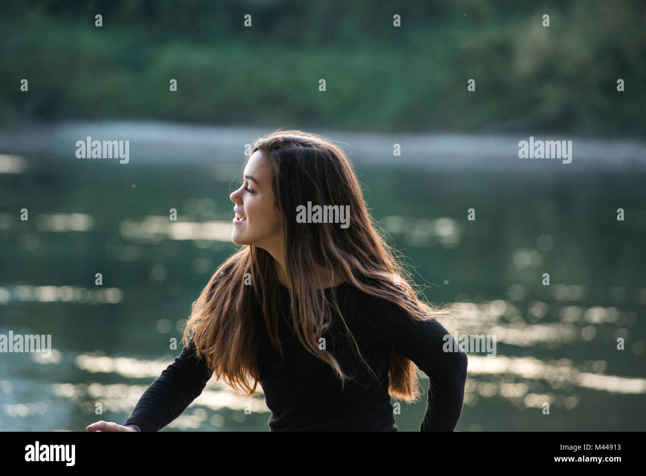 Glückliche junge Frau, die durch Fluss, Calolziocorte, Lombardei, Italien Stockfoto