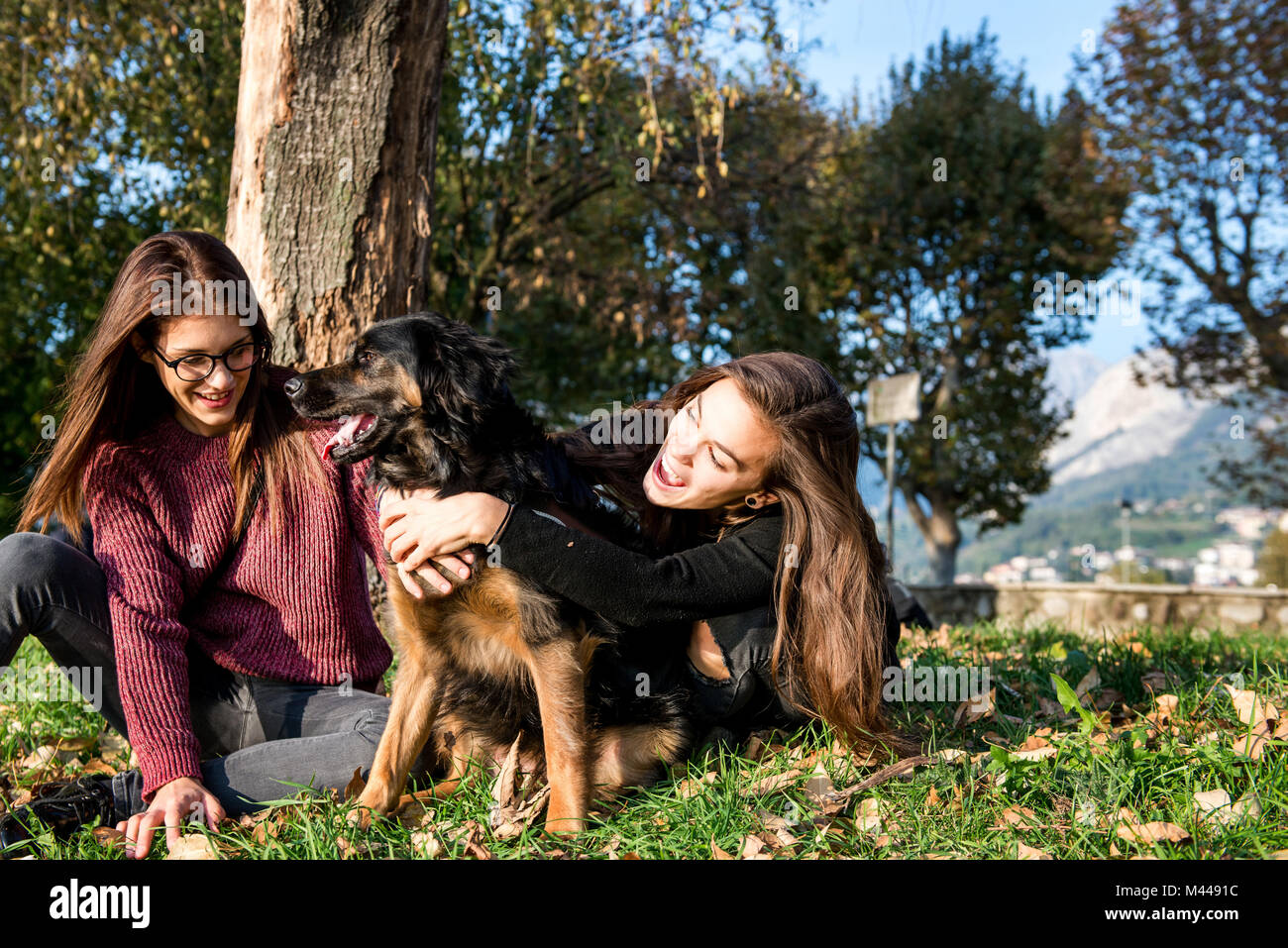 Zwei junge Frauen, die sich umarmen Hund, Calolziocorte, Lombardei, Italien Stockfoto