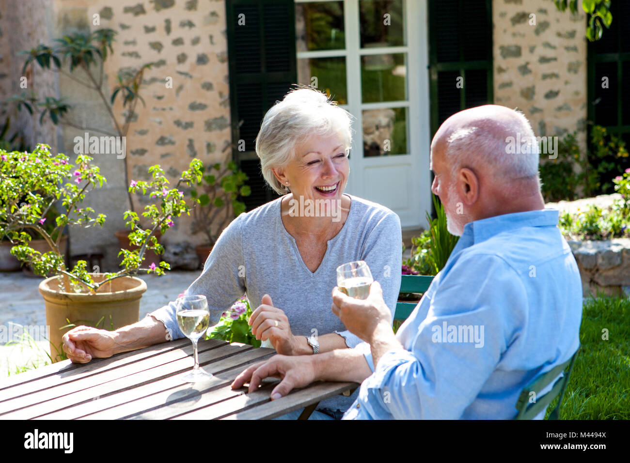 Ältere Paare im Garten sitzen, ein Glas Wein genießen. Stockfoto