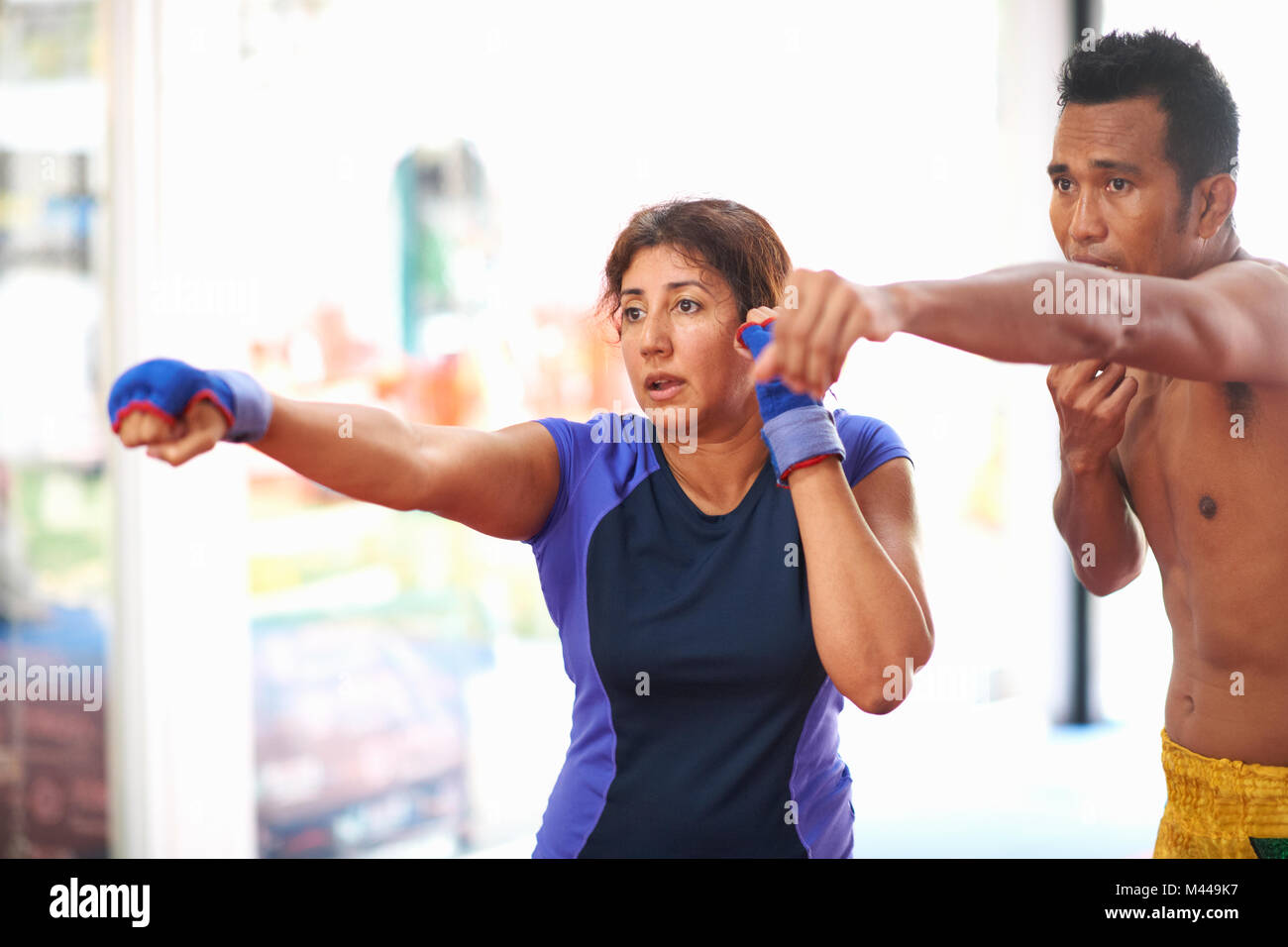 Reife Frau üben Boxing punch mit männlichen Trainer im Fitnessraum Stockfoto