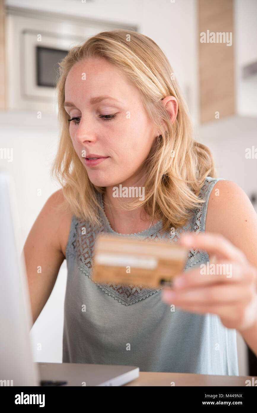 Junge Frau online Einkaufen mit Laptop auf dem Schreibtisch Stockfoto