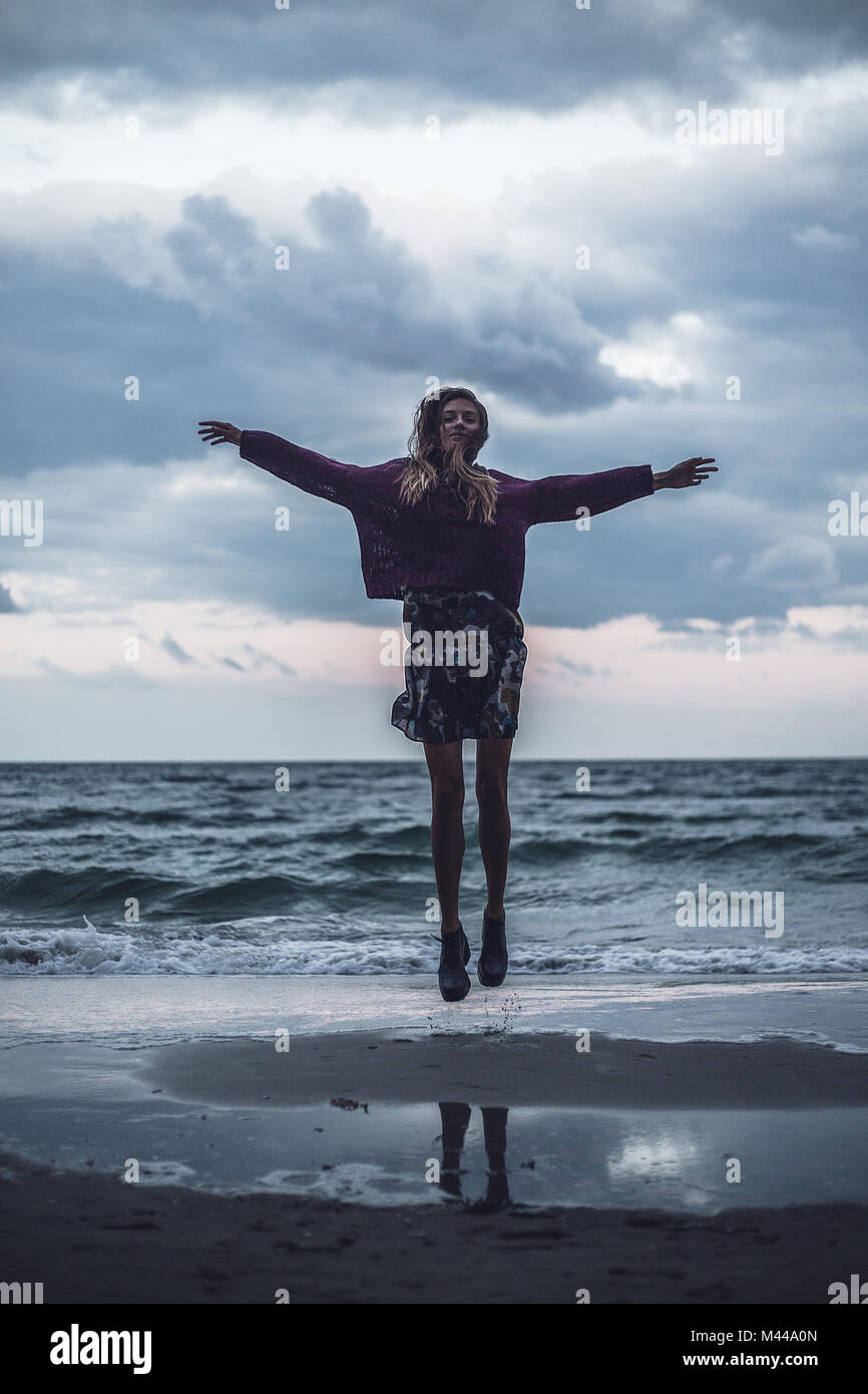 Porträt der jungen Frau am Strand bei Sonnenuntergang springen, Odessa, Ukraine Stockfoto