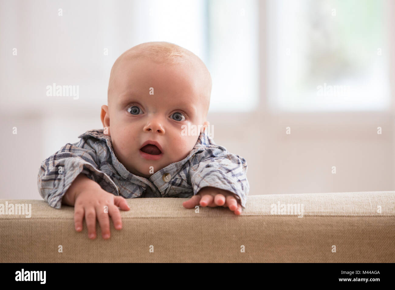 Portrait von baby boy, Klettern auf dem Sofa Stockfoto