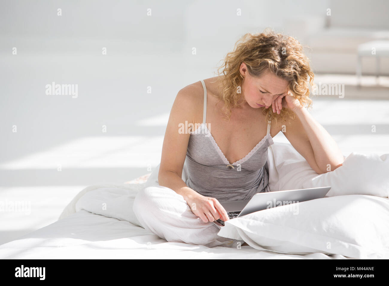 Frau zu Hause sitzt am Bett, mit laptop Stockfoto