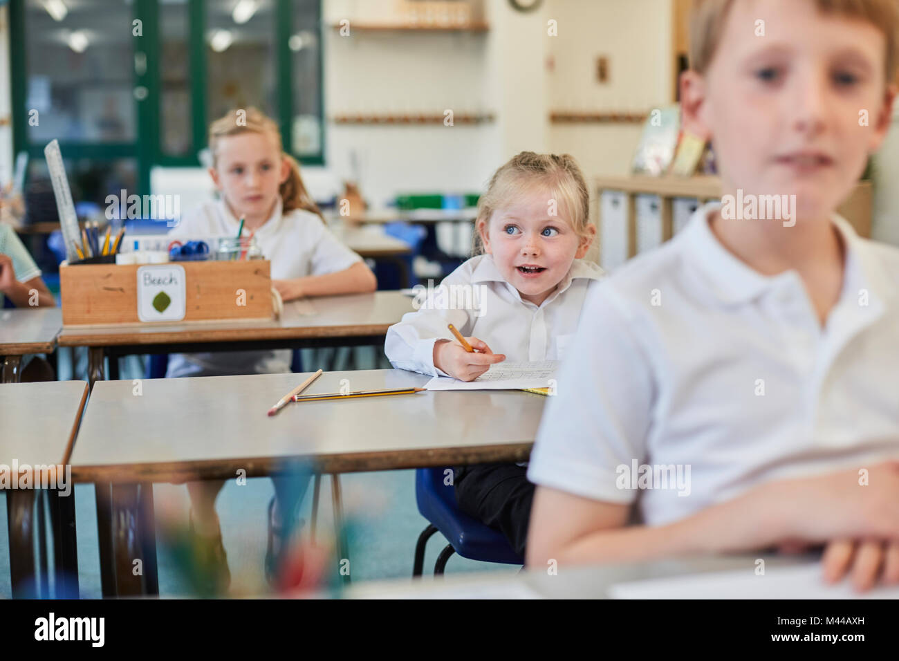 Primäre Schülerinnen und Junge tun Schularbeiten im Klassenzimmer Schreibtische Stockfoto