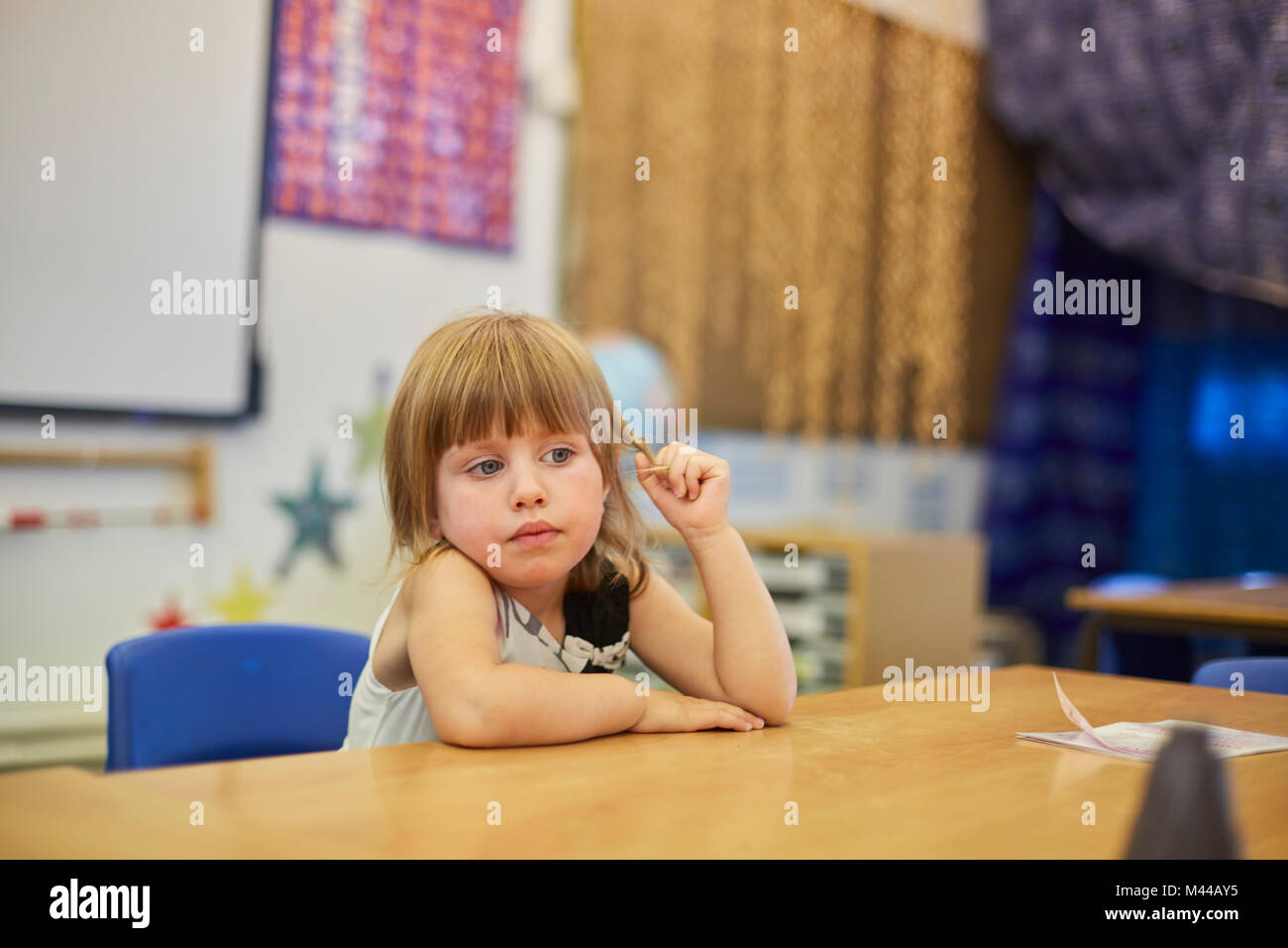 Primäre Schulmädchen das Hantieren mit Haar im Klassenzimmer Schreibtisch Stockfoto