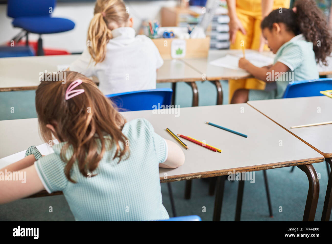 Schülerin schriftlich im Klassenzimmer Schreibtisch in der Grundschule Lektion, Rückansicht Stockfoto