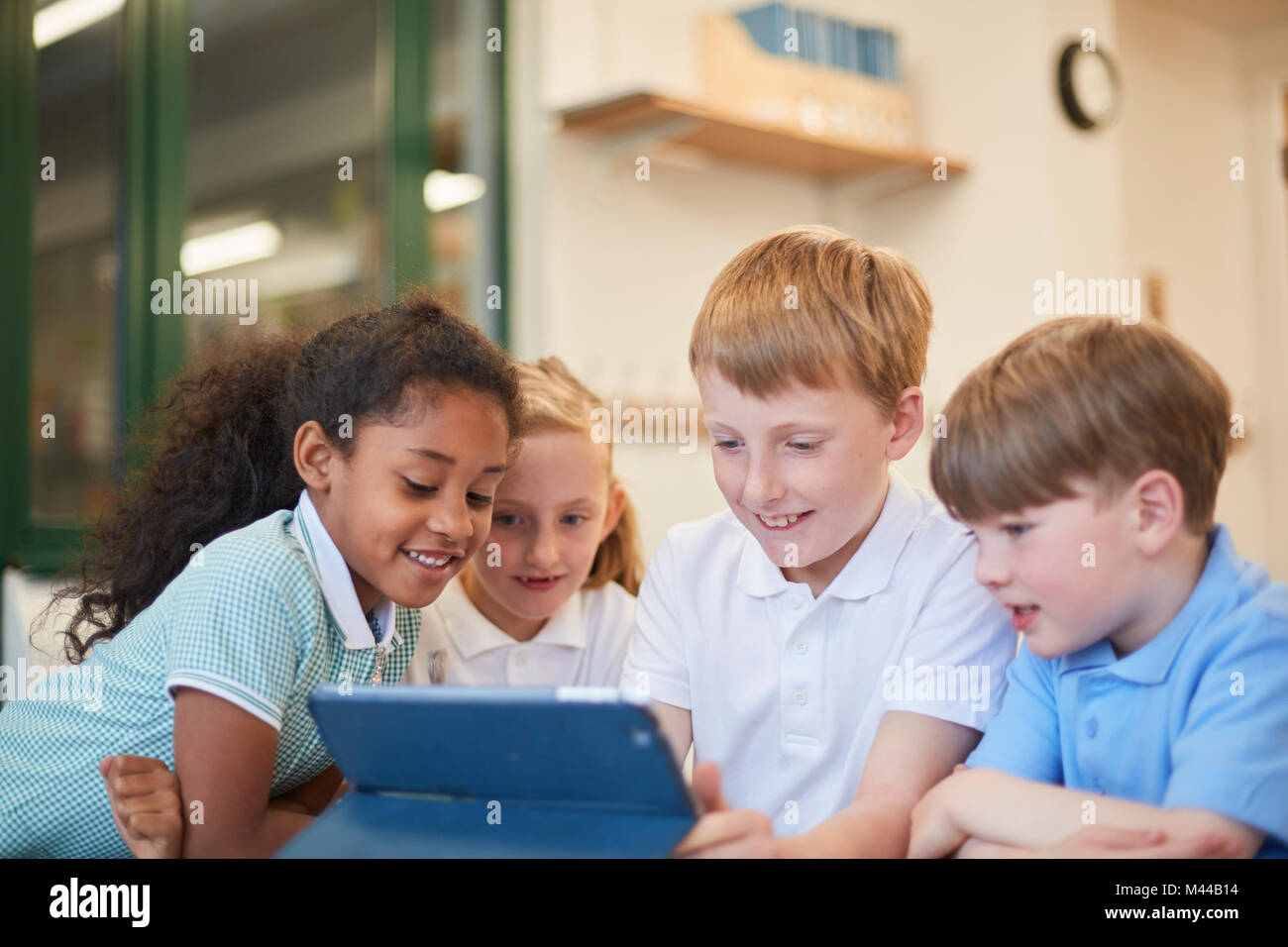 Schülerinnen und Schüler betrachten digital Tablet im Unterricht in der Grundschule Stockfoto