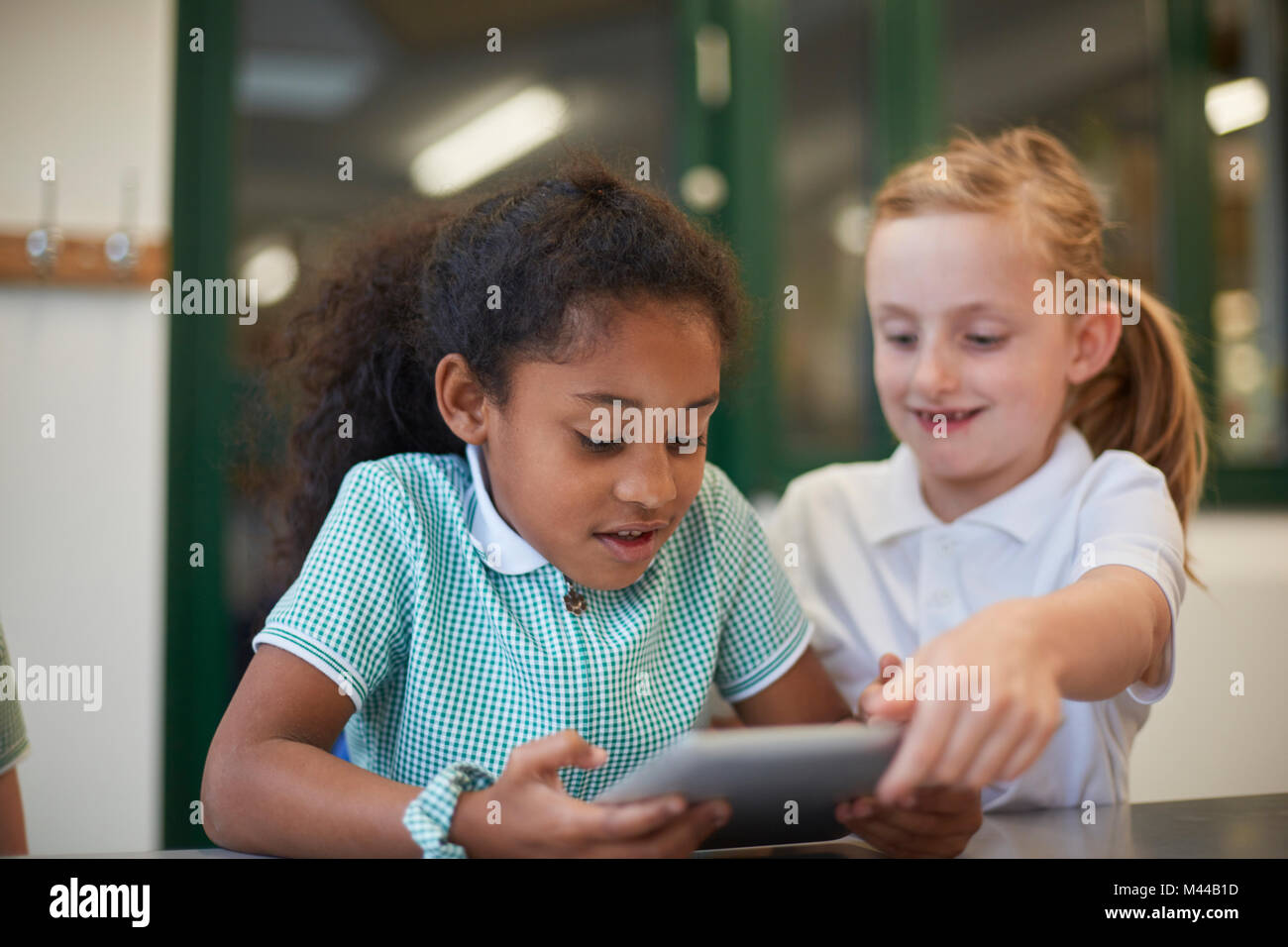 Zwei Schülerinnen suchen Bei digital Tablet im Unterricht in der Grundschule Stockfoto