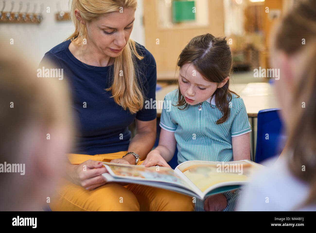 Lehrer mit Schülerinnen lesen Storybook im Unterricht in der Grundschule Stockfoto