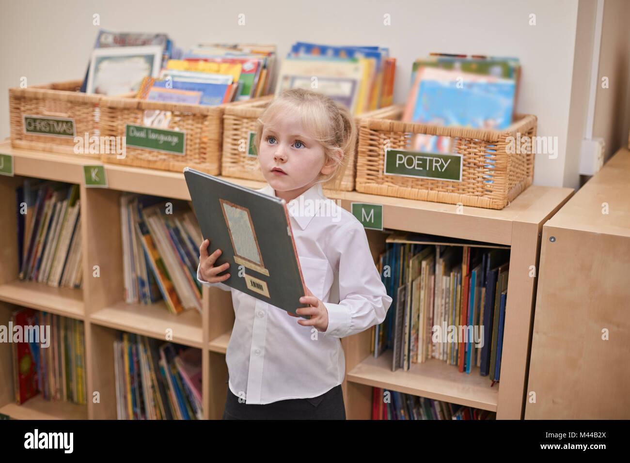 Süßes Schulmädchen holding Buch im Unterricht in der Grundschule Stockfoto
