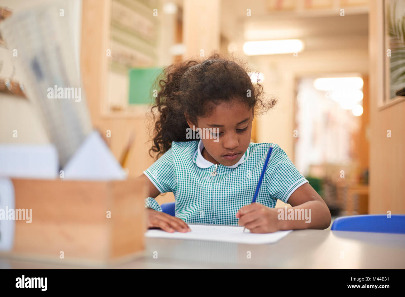 Schülerin schriftlich im Klassenzimmer Schreibtisch in der Grundschule Stockfoto