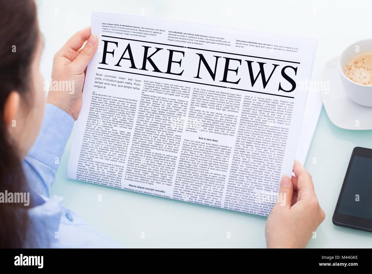 Direkt über der Geschäftsfrau lesen gefälschte Nachrichten Artikel auf Zeitung im Büro Stockfoto