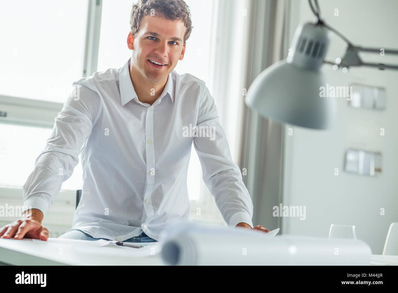 Portrait von selbstbewussten jungen Geschäftsmann am Schreibtisch im Büro sitzen Stockfoto