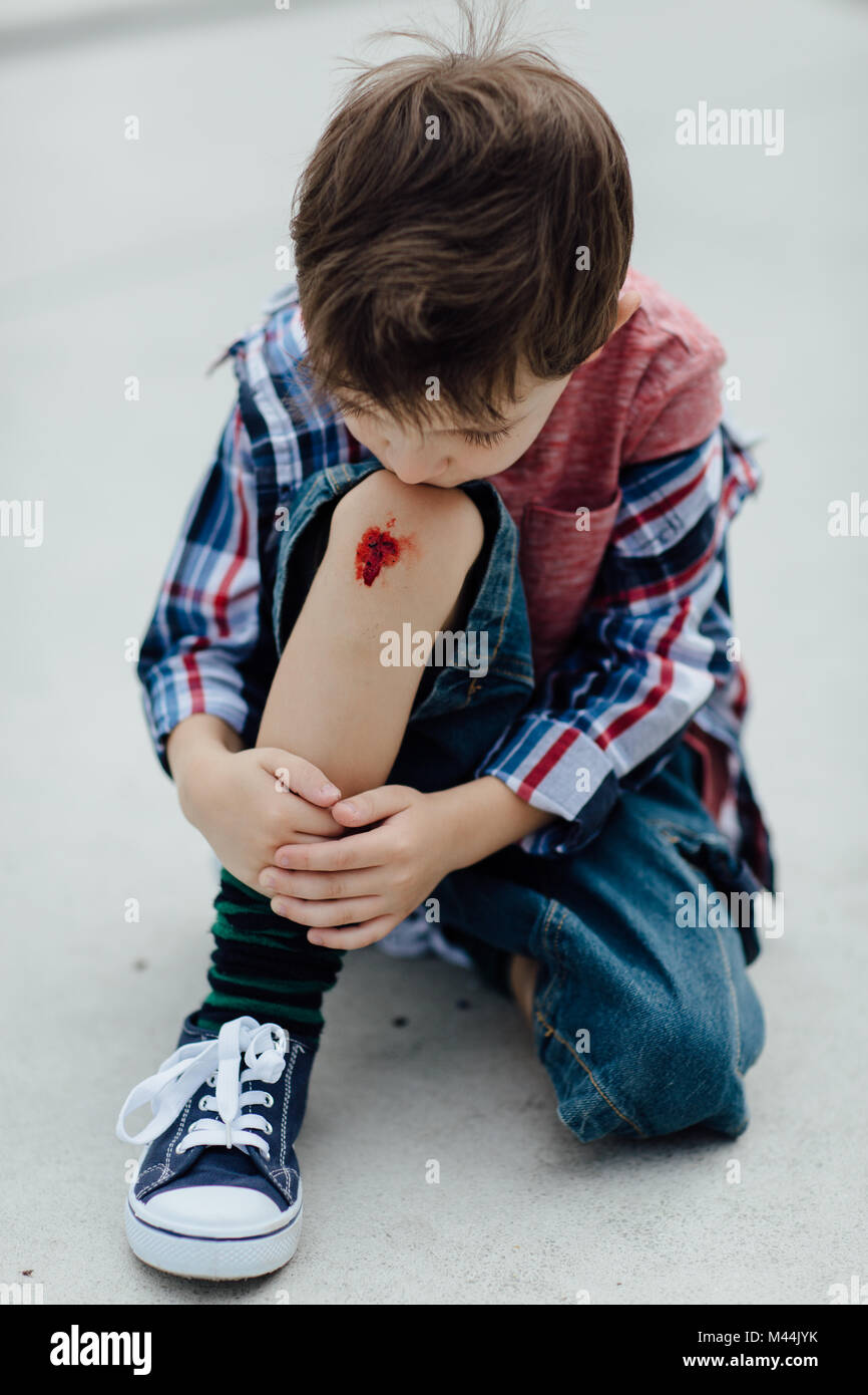 Porträt eines umgekippten Junge an seinem Knie gekratzt suchen Stockfoto