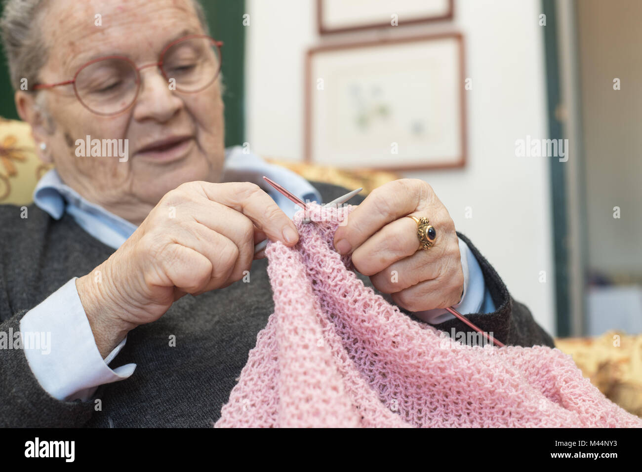 Ältere Frau entspannt zu Hause selektiven Fokus auf Händen closeup Stricken rosa Wolle Stockfoto