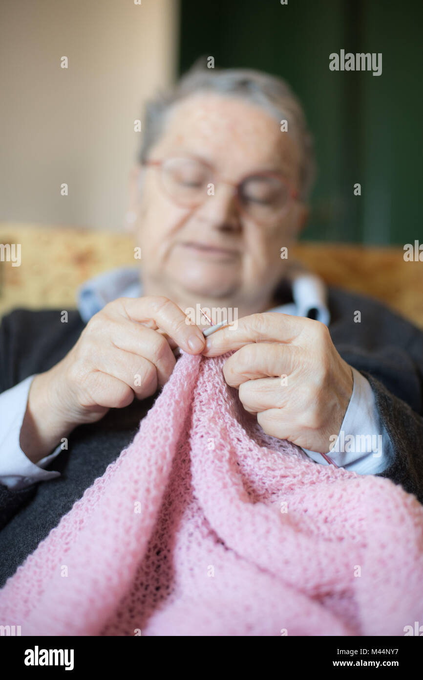 Ältere Frau entspannt zu Hause selektiven Fokus auf Händen closeup Stricken rosa Wolle Stockfoto