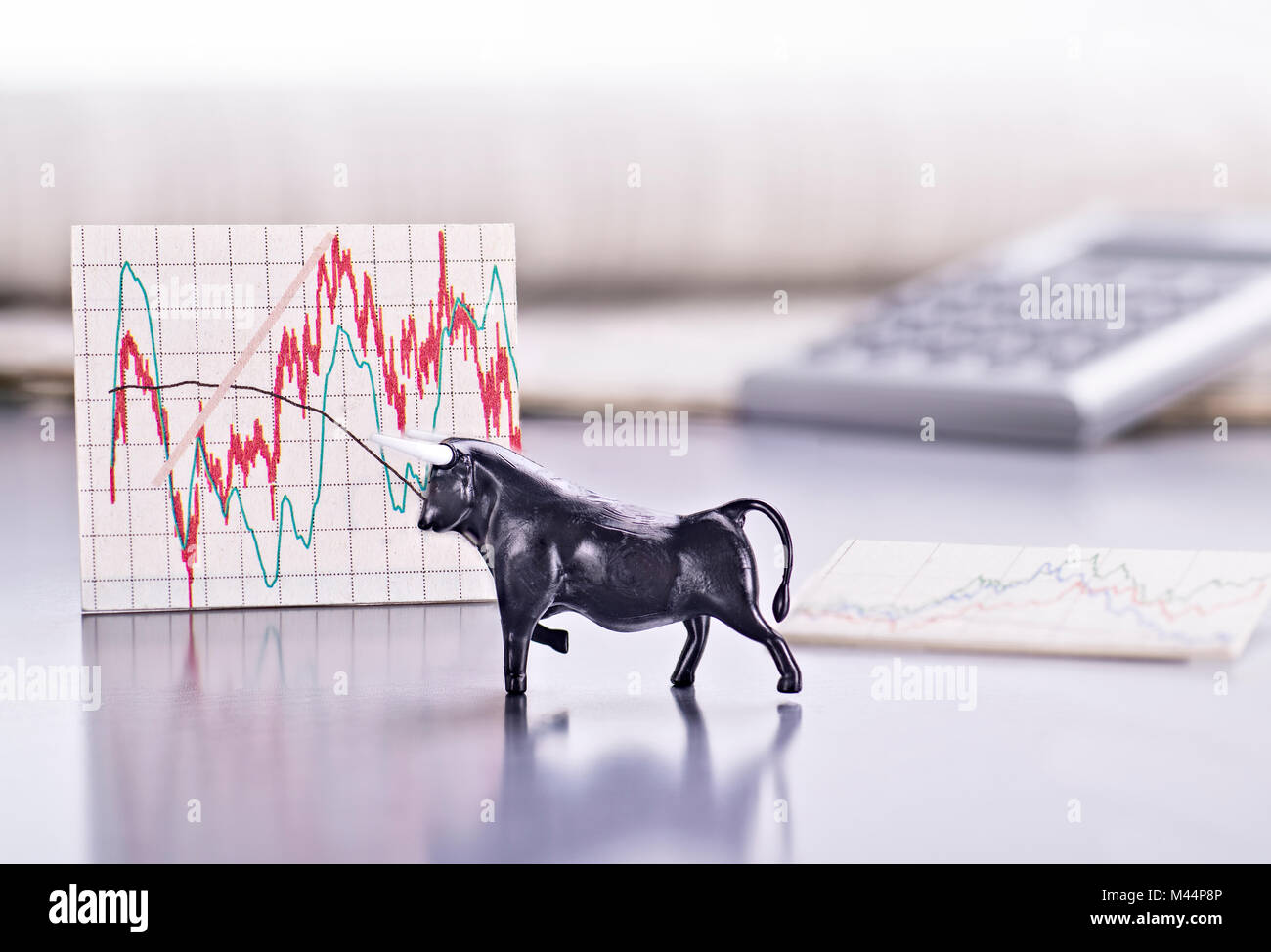 Schreibtisch mit der Figur des einen Jungstier und einen Graphen mit den Börsenkurs Stockfoto