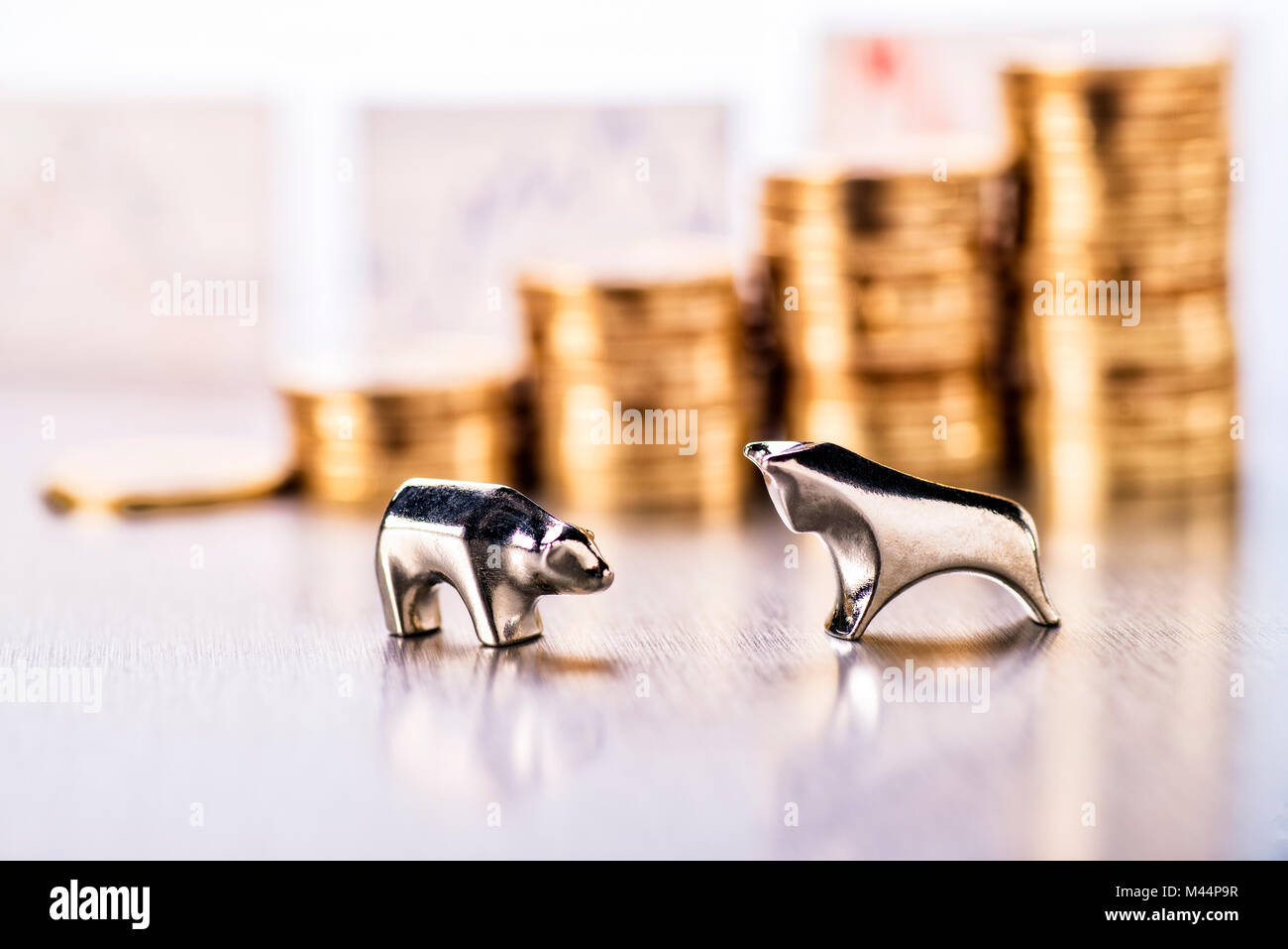 Bulle und Bär mit Stapeln von Münzen und die Aktienkurse im Hintergrund Stockfoto