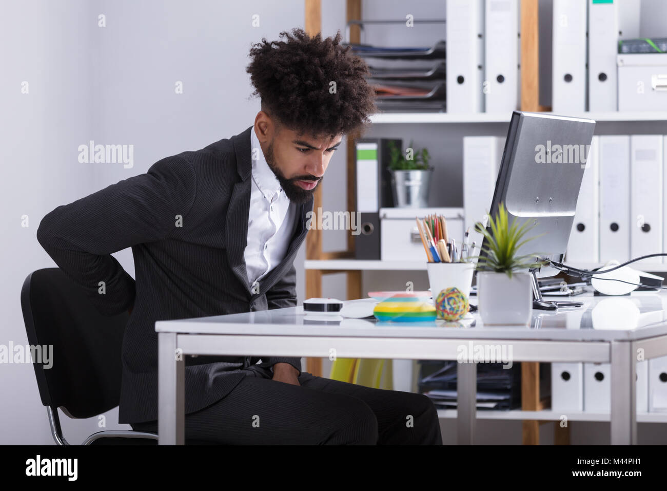 Junge Unternehmer leiden unter Rückenschmerzen im Büro Stockfoto