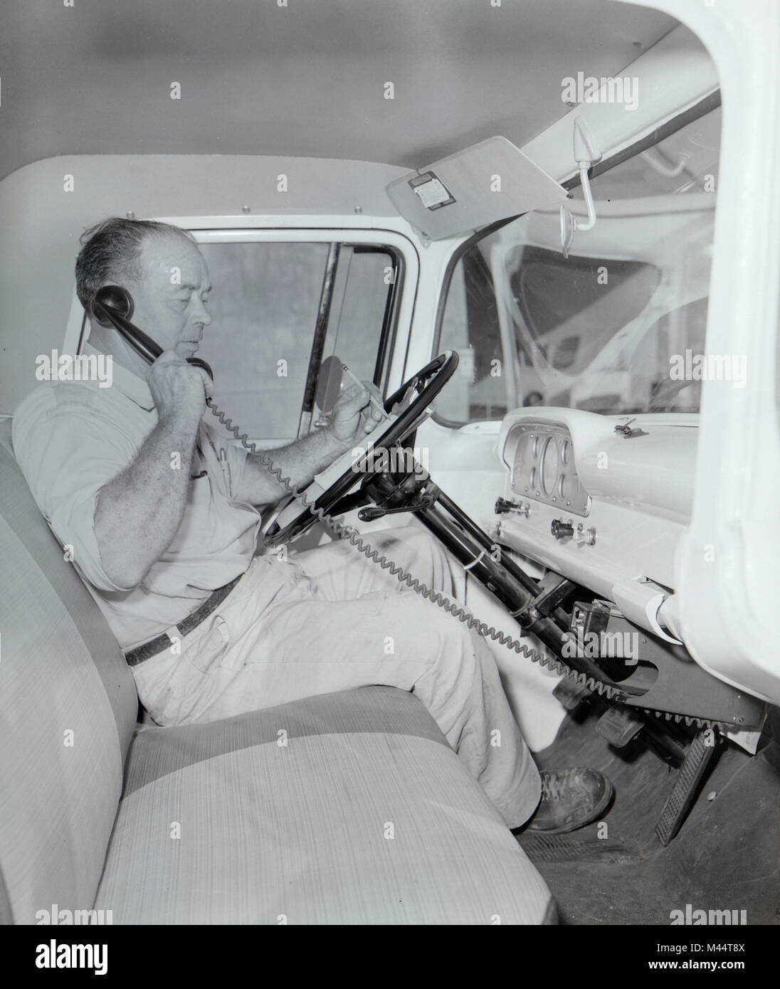 Anlieferung Treiber Gespräche auf einem frühen Funkgerät, Telefon in seinem Lkw, Ca. 1960. Stockfoto