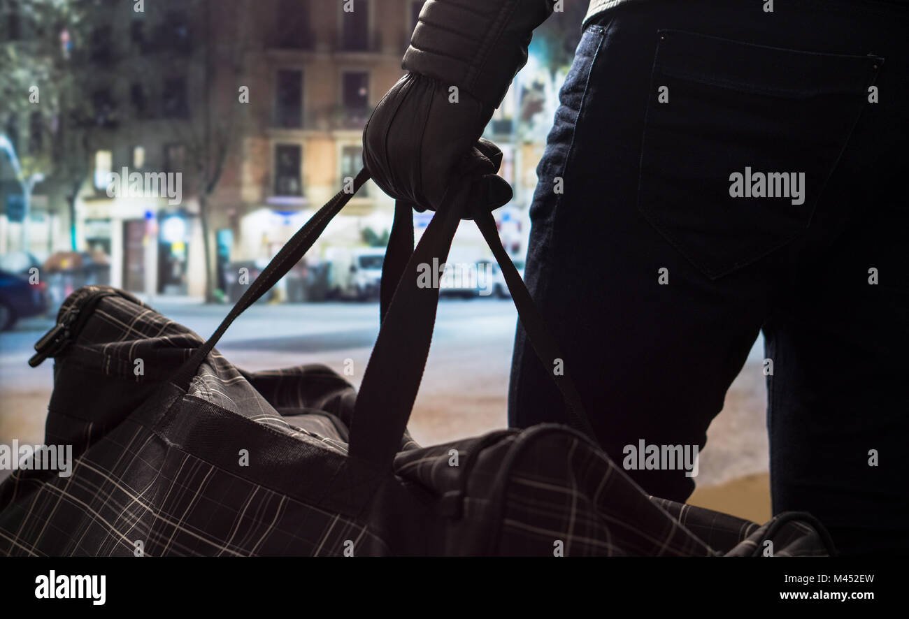 Terroristische und Holding schwarze Bombe Tasche in der Hand mit Leder Handschuhe. Mann Planung einer gefährlichen Explosion im Stadtzentrum. Bomber Selbstmord in der Nacht. Stockfoto
