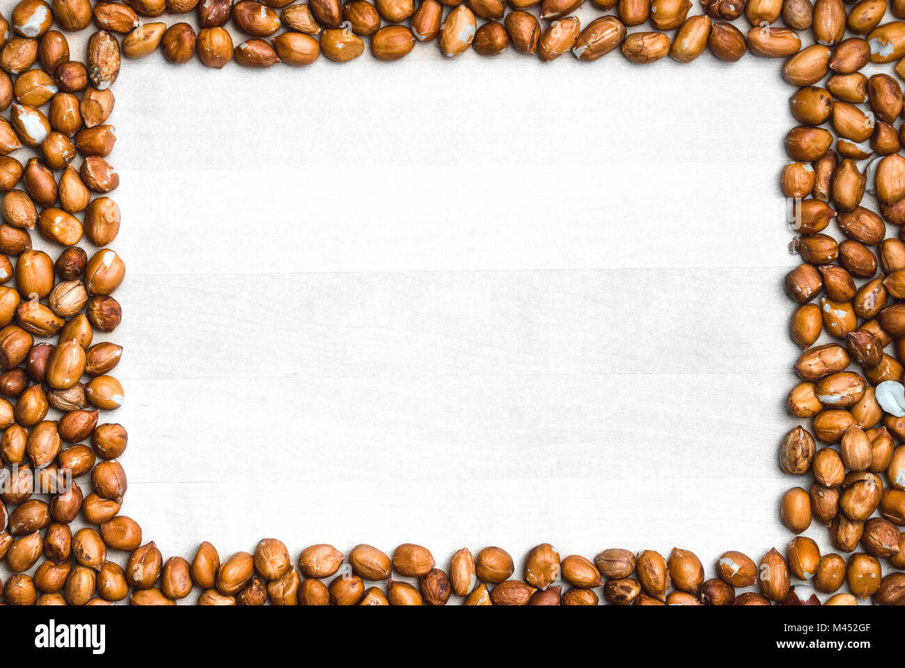 Peanut Rahmen Hintergrund. Weißes Holzbrett oder Tabelle mit Mutter Grenze in der Form von einem Rechteck umrahmt. Erdnuß-Kulisse und Vorlage. Stockfoto