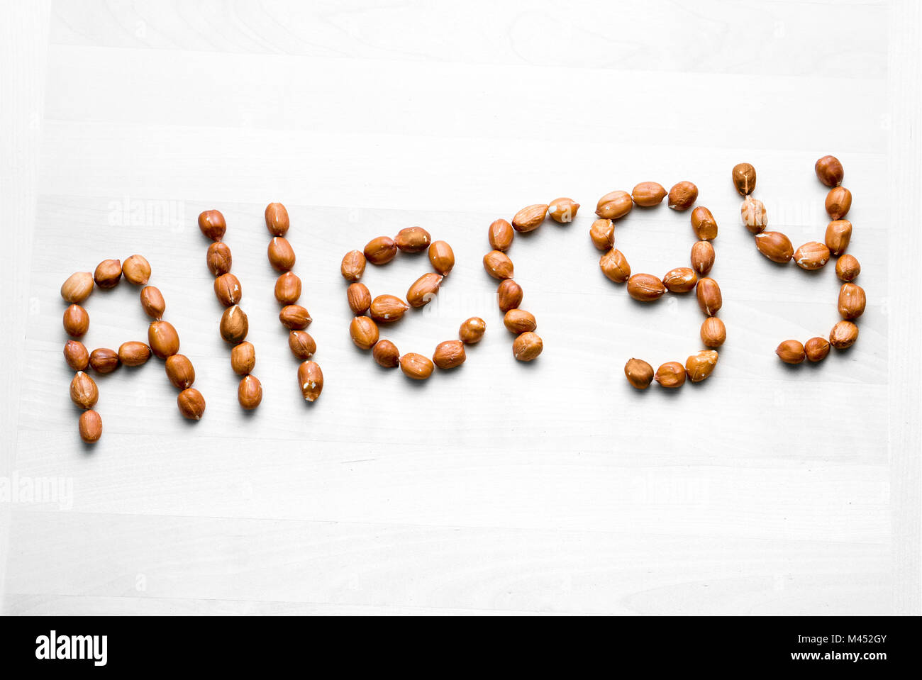 Allergie mit Erdnüssen geschrieben. Wort und Text aus Nüssen. Erdnüsse auf weissem Holztisch oder Board. Allergische Reaktion und Ernährung problem Konzept Stockfoto