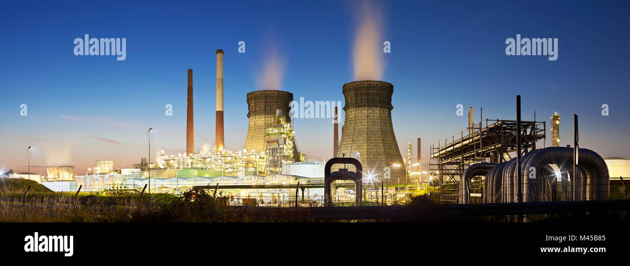 Panorama einer Ölraffinerie mit zwei Kühltürme und blauen Nachthimmel, einige Pipelines in den Vordergrund. Stockfoto