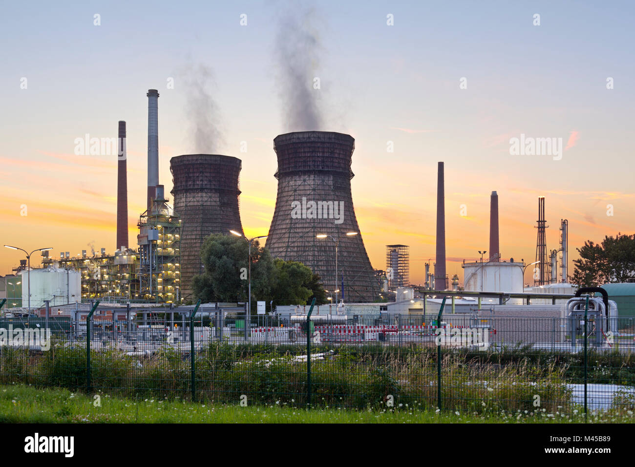 Eine Ölraffinerie mit zwei Kühltürme und bunten Abend Himmel. Stockfoto