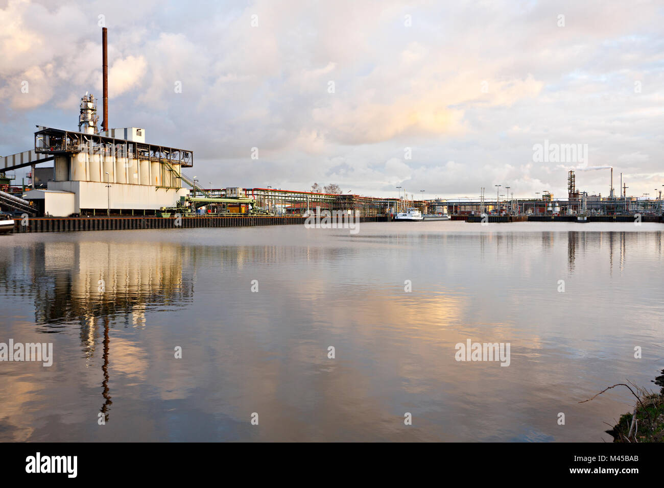 Eine alte Ölraffinerie mit angedockten Schiffe an einem Kanal. Stockfoto
