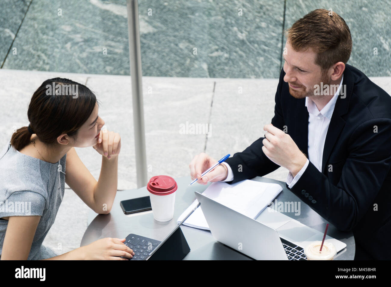Junge Unternehmer und Frau mit Laptop treffen im Straßencafé Stockfoto
