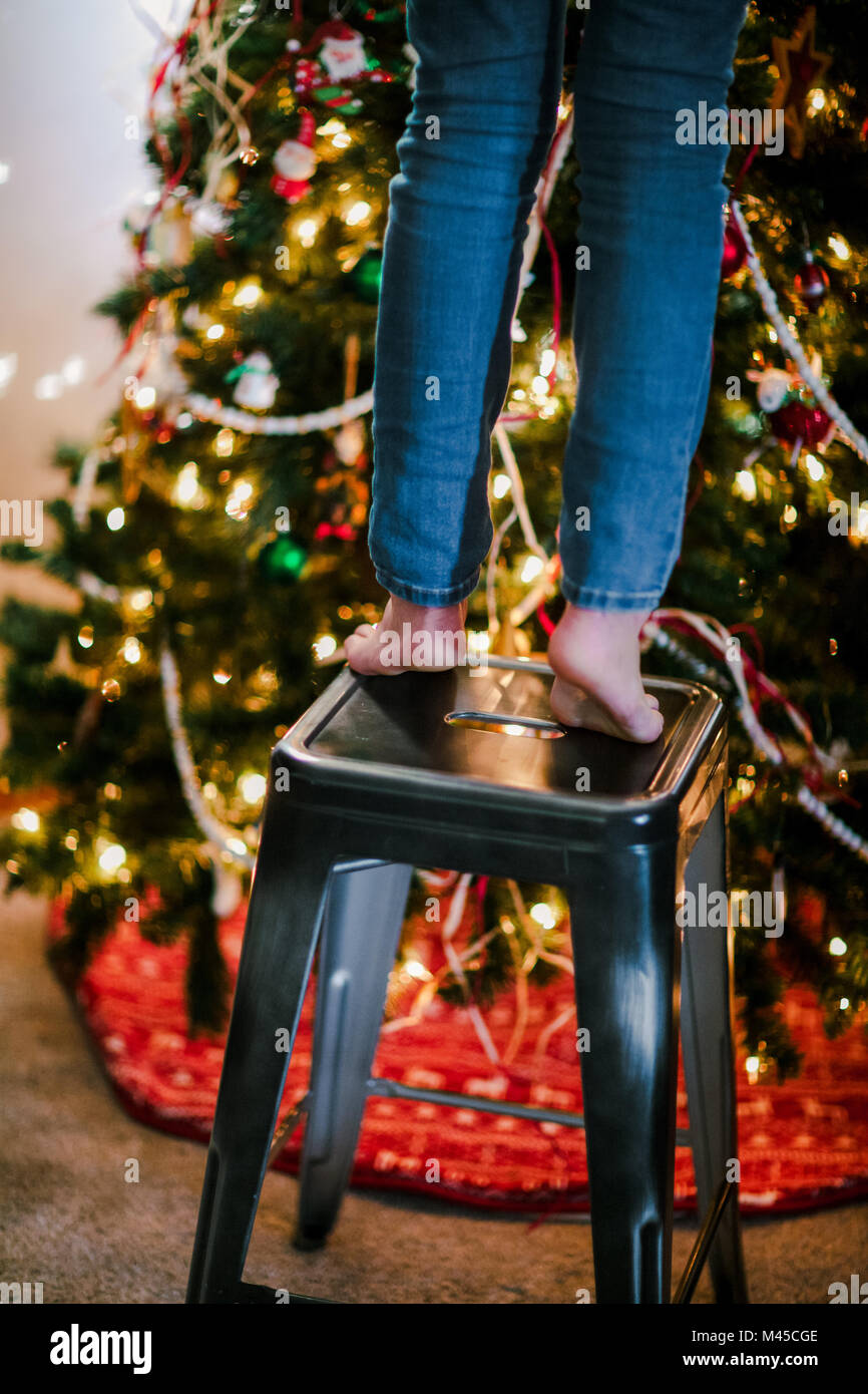 Kind auf Hocker bis Weihnachtsbaum zu schmücken Stockfoto