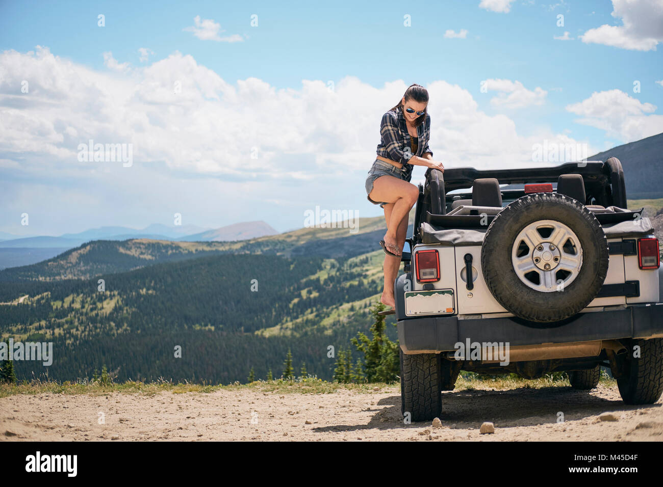 Junge Frau auf Straße Reise in Off Road Fahrzeug geparkt, Breckenridge, Colorado, USA, Klettern Stockfoto