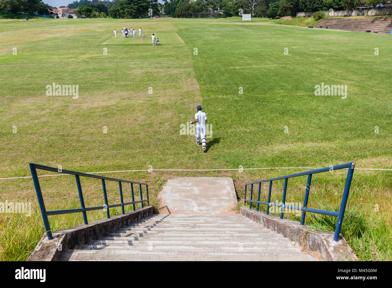 Cricket Spiel High School jugendliche Neue batsman aus oben genannten Schritte das Feld spielt. Stockfoto