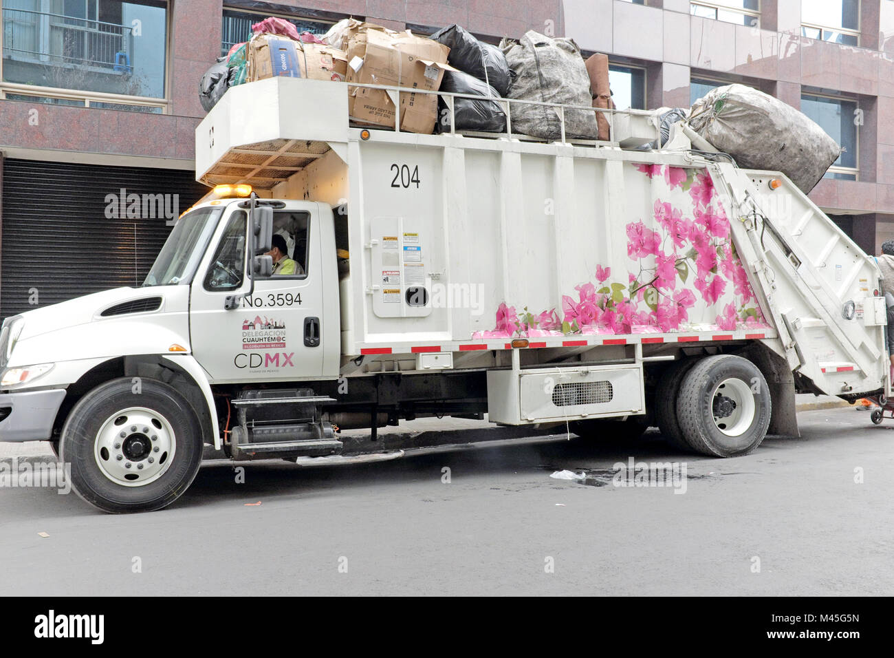 Eine gemalte Müllwagen macht Müll sammelt sich entlang einer Straße im historischen Teil von Mexiko City, Mexiko. Stockfoto