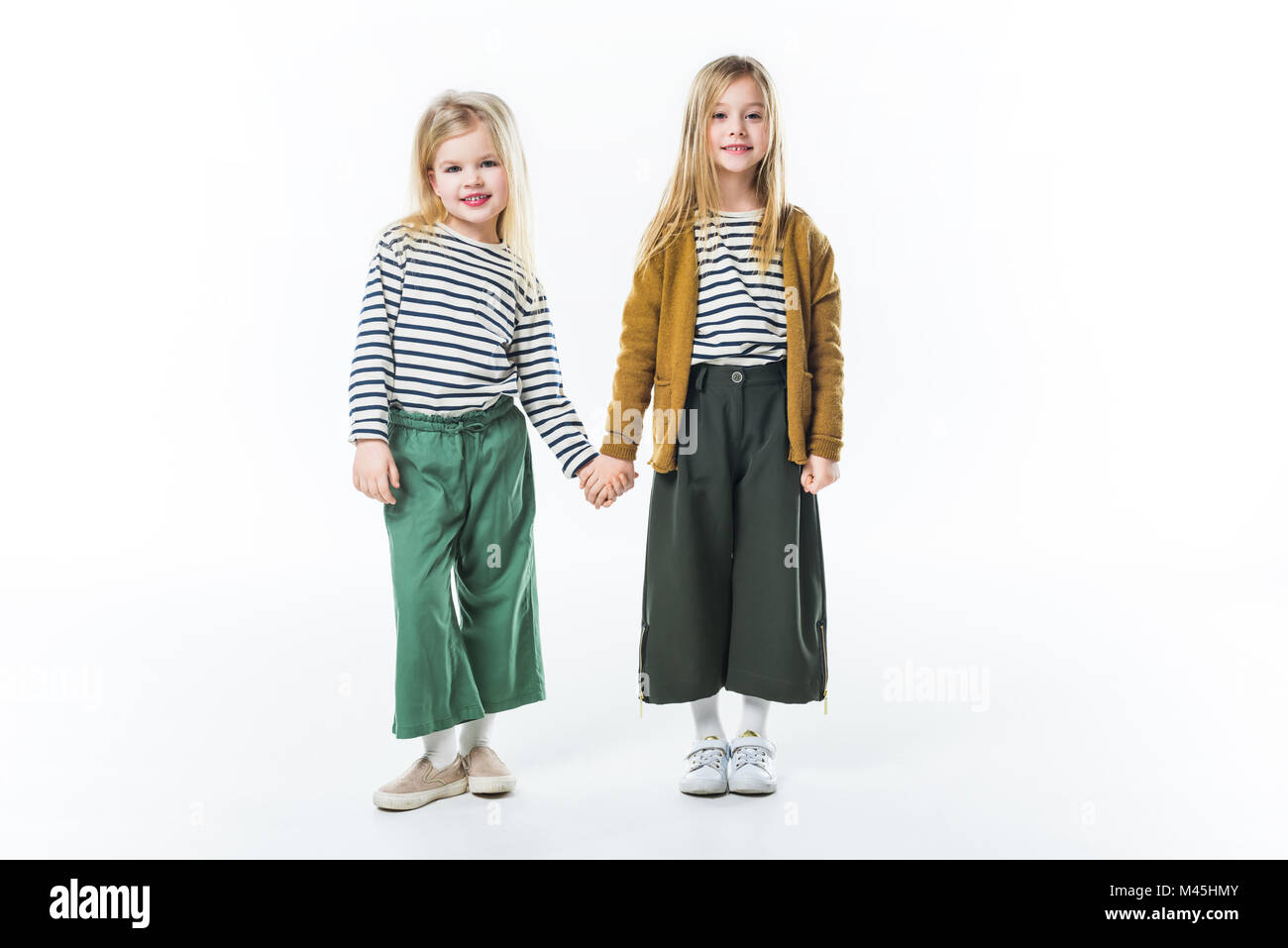 Elegante kleine Kinder halten sich an den Händen isoliert auf weißem Stockfoto