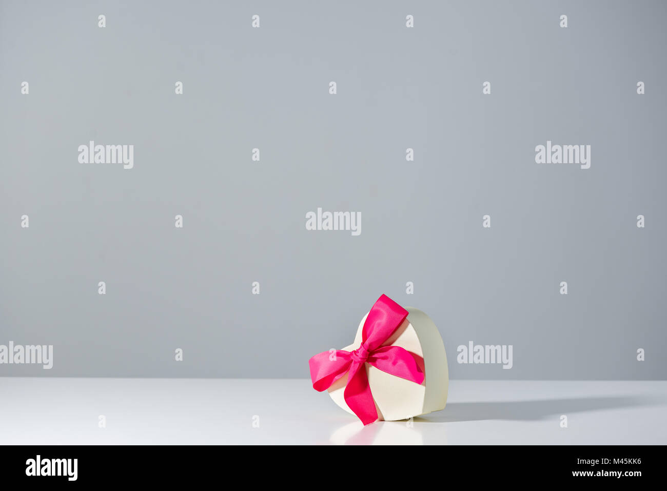 Herz Geschenkkarton mit Pink Ribbon auf Grau Stockfoto