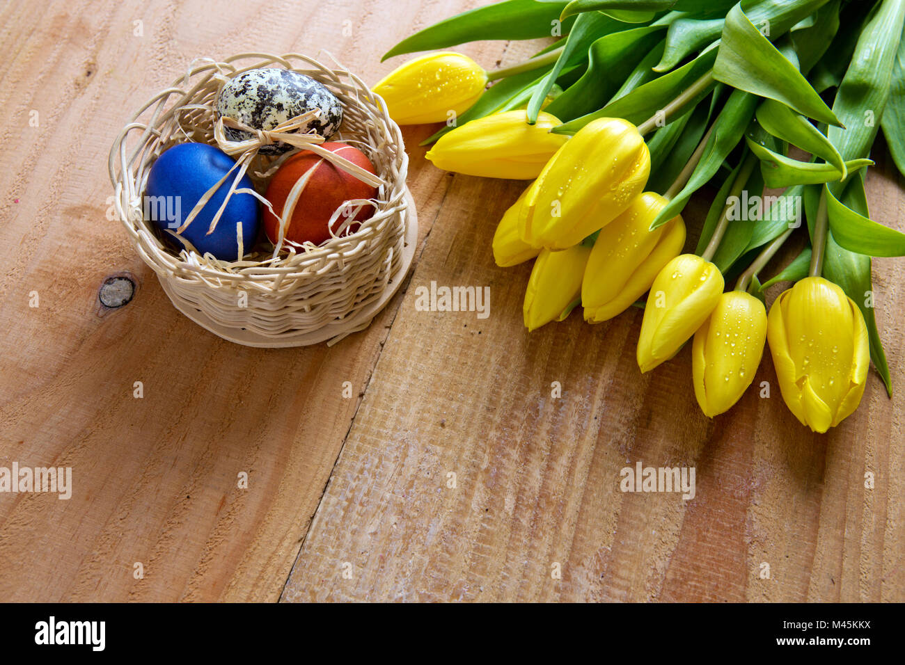 Ostern Korb mit bunten Eiern und gelbe Tulpen. Stockfoto