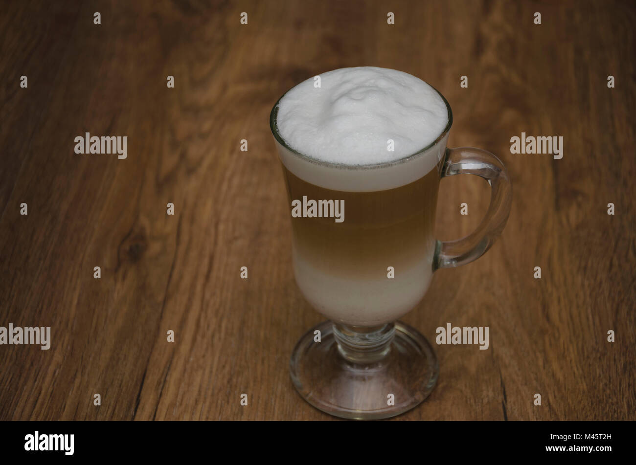 Heißes Getränk und Kaffee und Milch, Latte, Cappuccino, in einem schönen Glas Glas, auf einem Holztisch Stockfoto