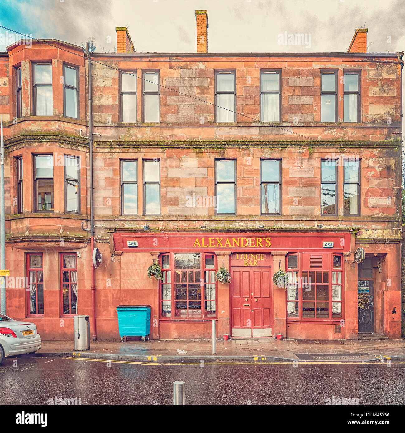 Ein roter Sandstein Mietshaus am unteren Ende von Alexander street in Clydebank mit der Street Bar im Erdgeschoss. Stockfoto