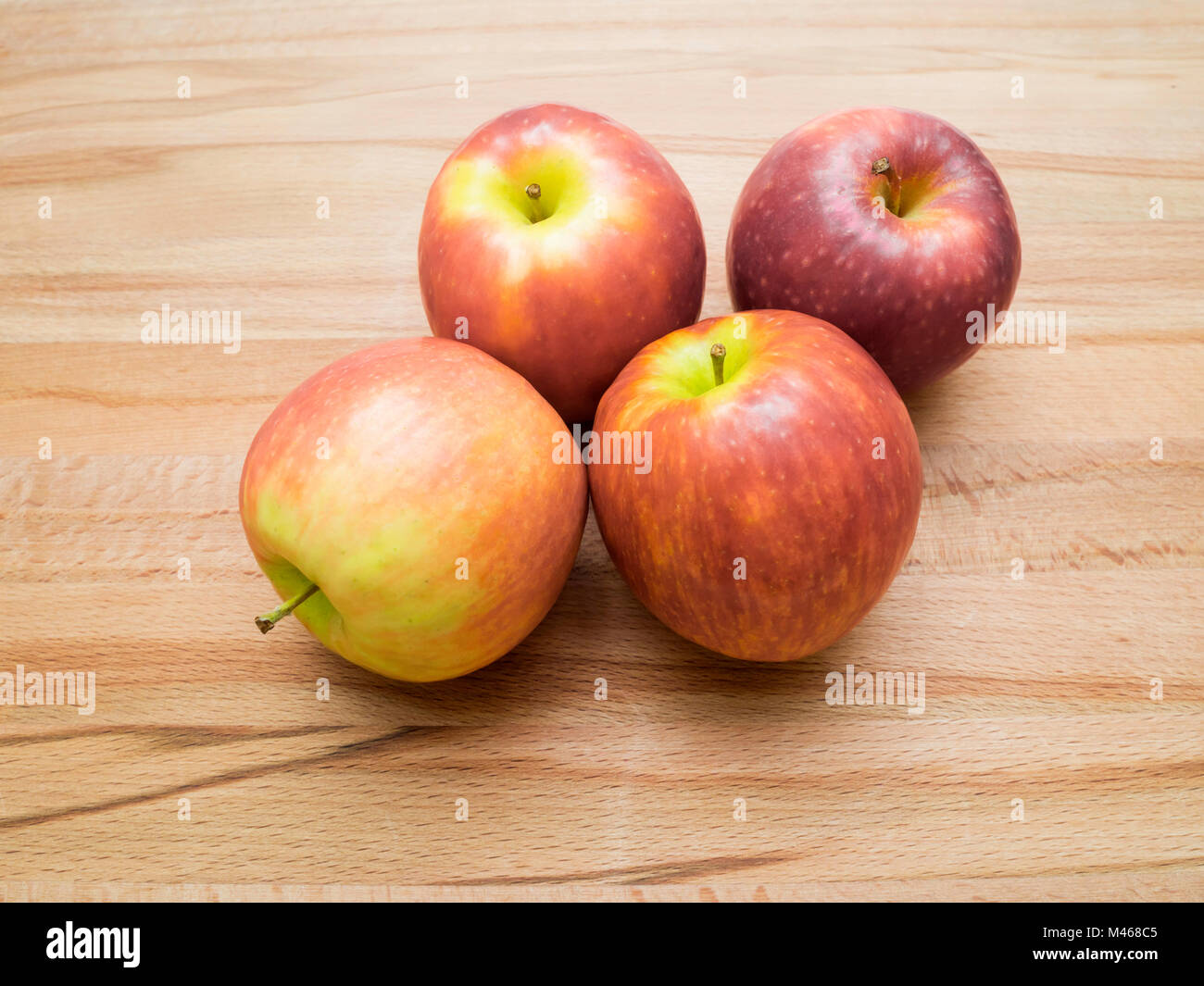 Vier bunte Pink Lady Äpfel Sorte Cripps Pink auf einem Holzbrett Stockfoto