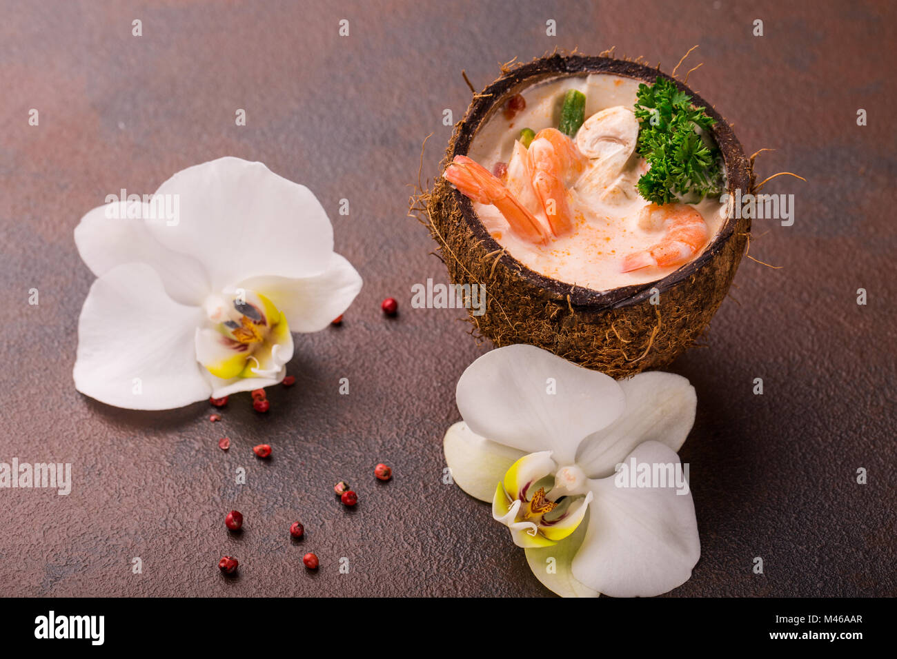 Lecker Garnelen Suppe mit Kokosmilch, kaffernlimette Blätter, Galgant, Chili und Zitronengras in einer Kokosnuss. Einrichtung von orchid Stockfoto