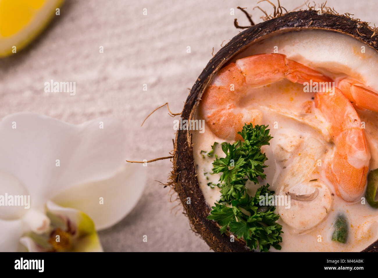 Lecker Garnelen Suppe mit Kokosmilch, kaffernlimette Blätter, Galgant, Chili und Zitronengras in einer Kokosnuss. Einrichtung von orchid Stockfoto