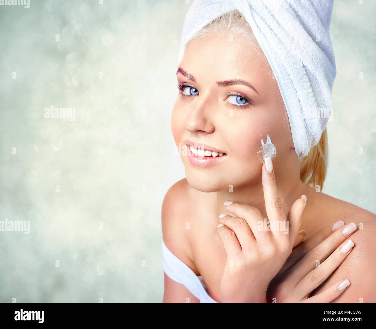 Nahaufnahme Porträt der Schönen lächelnde Frau mit Handtuch auf Haare, Anwendung, feuchtigkeitsspendende Creme Stockfoto