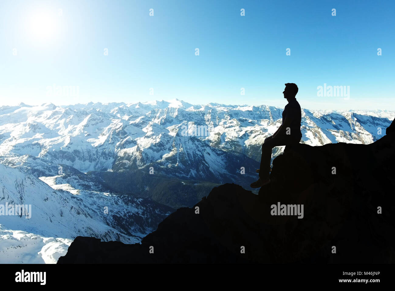 Silhouette eines Mannes mit Rucksack an den Rand der Klippe zu erkunden Anzeigen Stockfoto